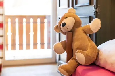a teddy bear sitting on top of a bed at Trafisolerhof in Vols am Schlern