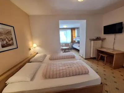 a hotel room with two beds and a desk at Gasthof Moarwirt in Colle Isarco