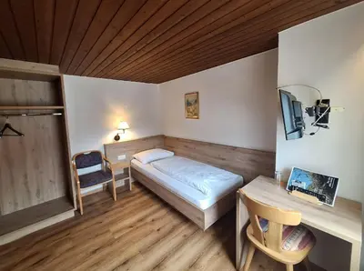 a small bedroom with a bed and a desk at Gasthof Moarwirt in Colle Isarco
