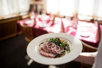 a person holding a plate of food on a table at Gasthof Moarwirt in Colle Isarco