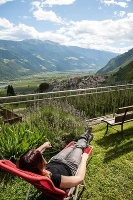 a woman laying in a hammock overlooking a valley at Obermairhof in Parcines
