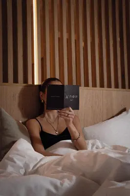 a woman laying in bed reading a book at Anett hotel in Vipiteno