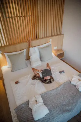 a woman laying on a bed with a book at Anett hotel in Vipiteno