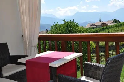 a table and chairs on a balcony with a view at Gästehaus Pfuss in Caldaro