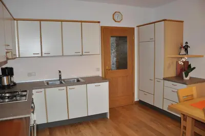a kitchen with white cabinets and a wooden floor at Gästehaus Pfuss in Caldaro