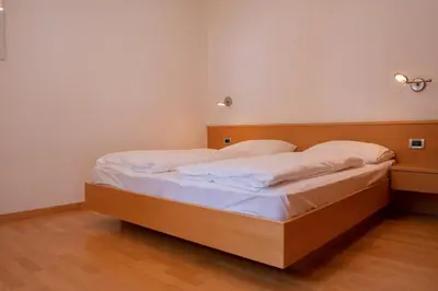 a bedroom with a wooden bed with white sheets at Ferienwohnung im Haus Texel V in Parcines