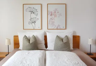 a bed with two pillows and two pictures on the wall at Appartement Karnutsch in Schenna