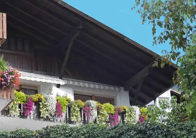 a white house with flowers on a fence at Appartement Karnutsch in Schenna