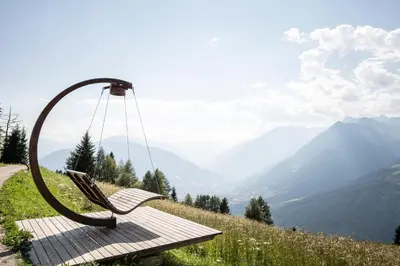a swinging chair on a hill with a view of mountains at Taser Alm in Schenna