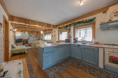 a kitchen with blue cabinets and a living room at Ciaseles a due passi da Cortina d'Ampezzo in San Vito di Cadore