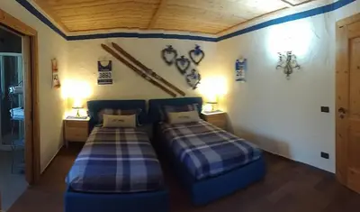 two twin beds in a room with two lamps at Maso Valfloriana in Valfloriana