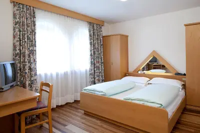 a bedroom with a bed and a desk and a television at Ciasa Roby in San Cassiano