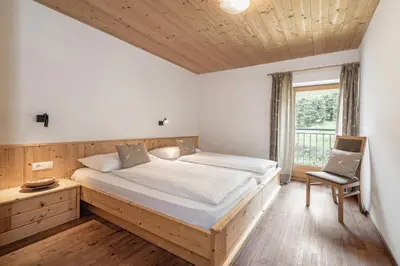 a bedroom with a bed and a chair and a window at Appartements Toni in Feldthurns