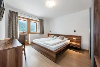 a bedroom with a bed and a desk and a window at Appartements Toni in Feldthurns
