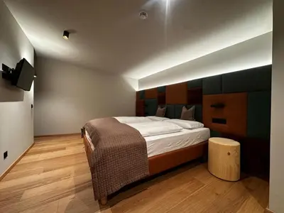a bedroom with a large bed and a tv at Ciasa Milandura NEW SUMMER 2025 in San Cassiano
