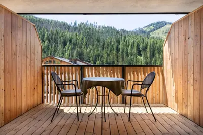 a table and two chairs on a deck with a view at Ciasa Milandura NEW SUMMER 2025 in San Cassiano