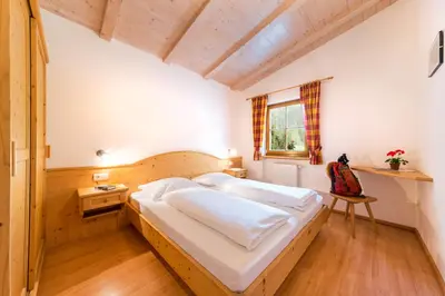a bedroom with a bed and a desk and a window at Pardellerhof Lüsen in Luson