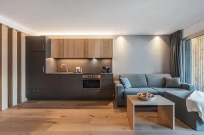 a living room with a blue couch and a kitchen at Dornsberg Panoramic Apartments in Schenna