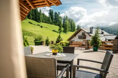 a table and chairs on a patio with a view at Taela Apartments in San Cassiano