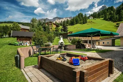 a sandbox with toys in the sand in a backyard at Taela Apartments in San Cassiano