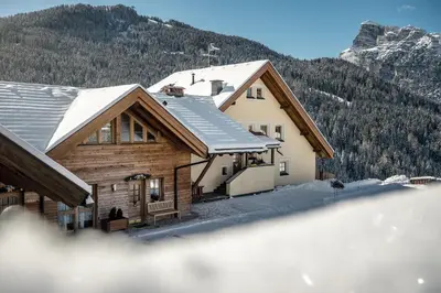 a house in the mountains with snow on the roof at Taela Apartments in San Cassiano