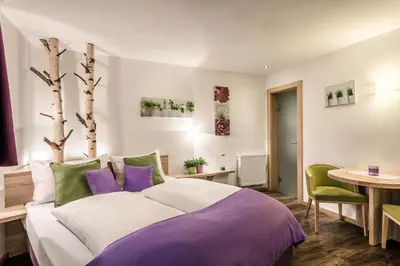 a bedroom with a large bed with purple and green pillows at Taela Apartments in San Cassiano