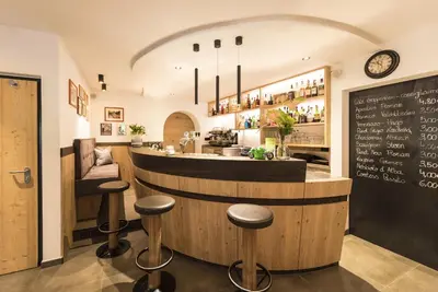 a restaurant with a bar with stools and a chalkboard at Hotel Florian in Selva di Val Gardena