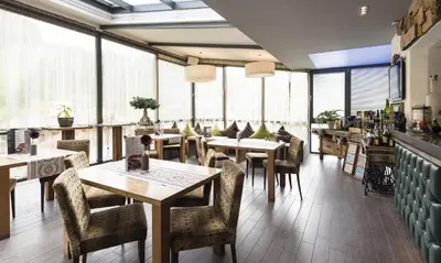 a restaurant with tables and chairs and large windows at Hotel Florian in Selva di Val Gardena