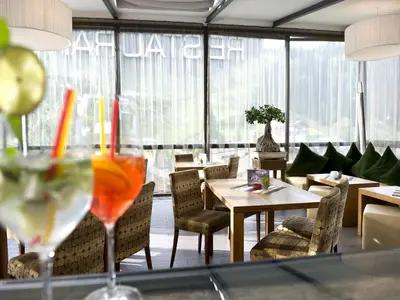 a restaurant with tables and chairs and a drink at Hotel Florian in Selva di Val Gardena