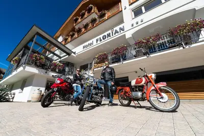 two men on motorcycles parked in front of a building at Hotel Florian in Selva di Val Gardena