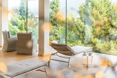 a living room with chairs and a large window at Hotel Gschwangut in Lana