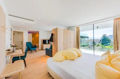 a bedroom with a bed and a living room at Hotel Gschwangut in Lana