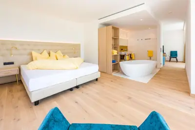 a bedroom with a bed and a bath tub at Hotel Gschwangut in Lana