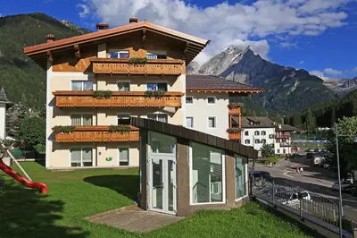 a building with a balcony with a mountain in the background at Hotel Astoria in Canazei