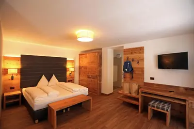 a bedroom with a bed and a tv and a couch at Hotel Astoria in Canazei