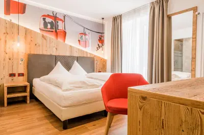 a bedroom with a bed and a red chair at Hotel Astoria in Canazei