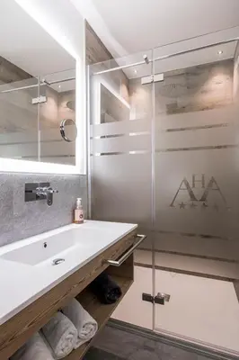 a bathroom with a sink and a glass shower at Hotel Astoria in Canazei