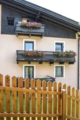 a house with a wooden fence and flower boxes at Apartments Heidenberger Fienili in Colle Isarco