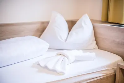 a bed with white pillows and a towel on it at Apartments Heidenberger Fienili in Colle Isarco