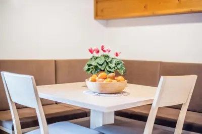 a bowl of oranges on a table with two chairs at Apartments Heidenberger Fienili in Colle Isarco