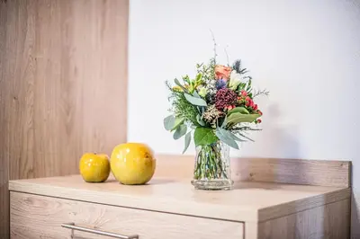 a vase of flowers and two apples on a table at Apartments Heidenberger Delle Scuole in Colle Isarco