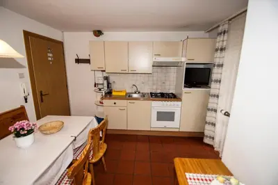 a kitchen with white cabinets and a table and a table and chairs at Apartments Heidenberger Delle Scuole in Colle Isarco