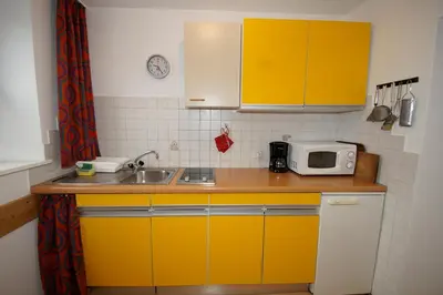 a small kitchen with yellow cabinets and a microwave at Apartments Heidenberger Delle Scuole in Colle Isarco