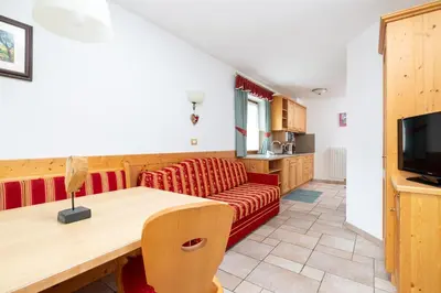 a living room with a red couch and a television at Frara Residence Apartments in San Cassiano