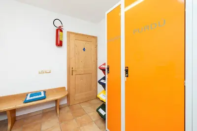 an orange locker in a room with a bench and a door at Frara Residence Apartments in San Cassiano