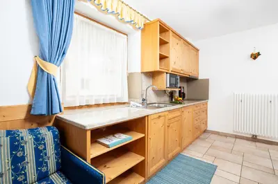 a kitchen with wooden cabinets and a sink and a window at Frara Residence Apartments in San Cassiano