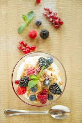 a bowl of yogurt with berries in the shape of a face at Berghotel Miramonti in Tesero