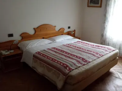 a bedroom with a bed with a quilt on it at Hotel Villa Agomer in Canazei