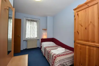 a small bedroom with a bed and a window at Hotel Villa Agomer in Canazei