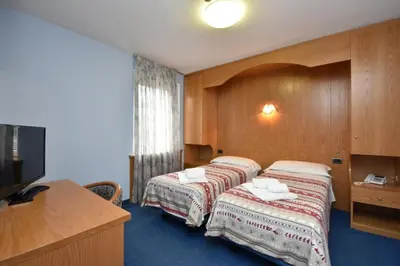 a hotel room with two beds and a flat screen tv at Hotel Villa Agomer in Canazei